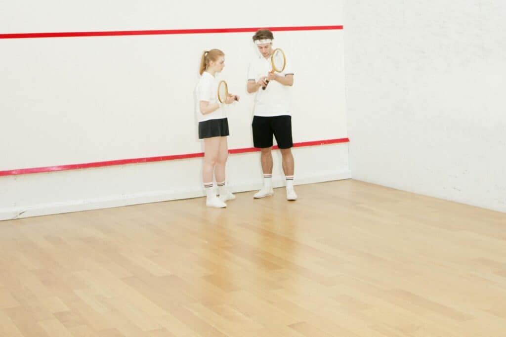 Two people in a squash court getting ready for the game