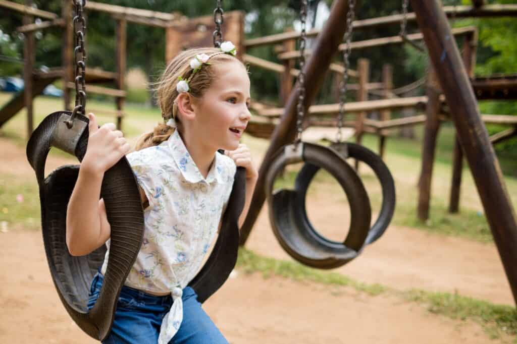 A girl sitting on a swing at the park