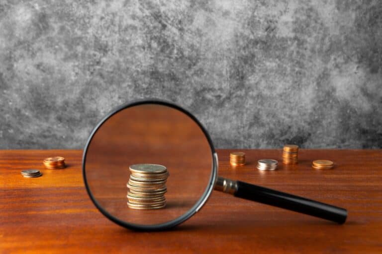 Coins on the table enlarged by a magnifying glass in the concept of 'What Are the Hidden Costs in Home Removals Services When Moving to Finchley?'